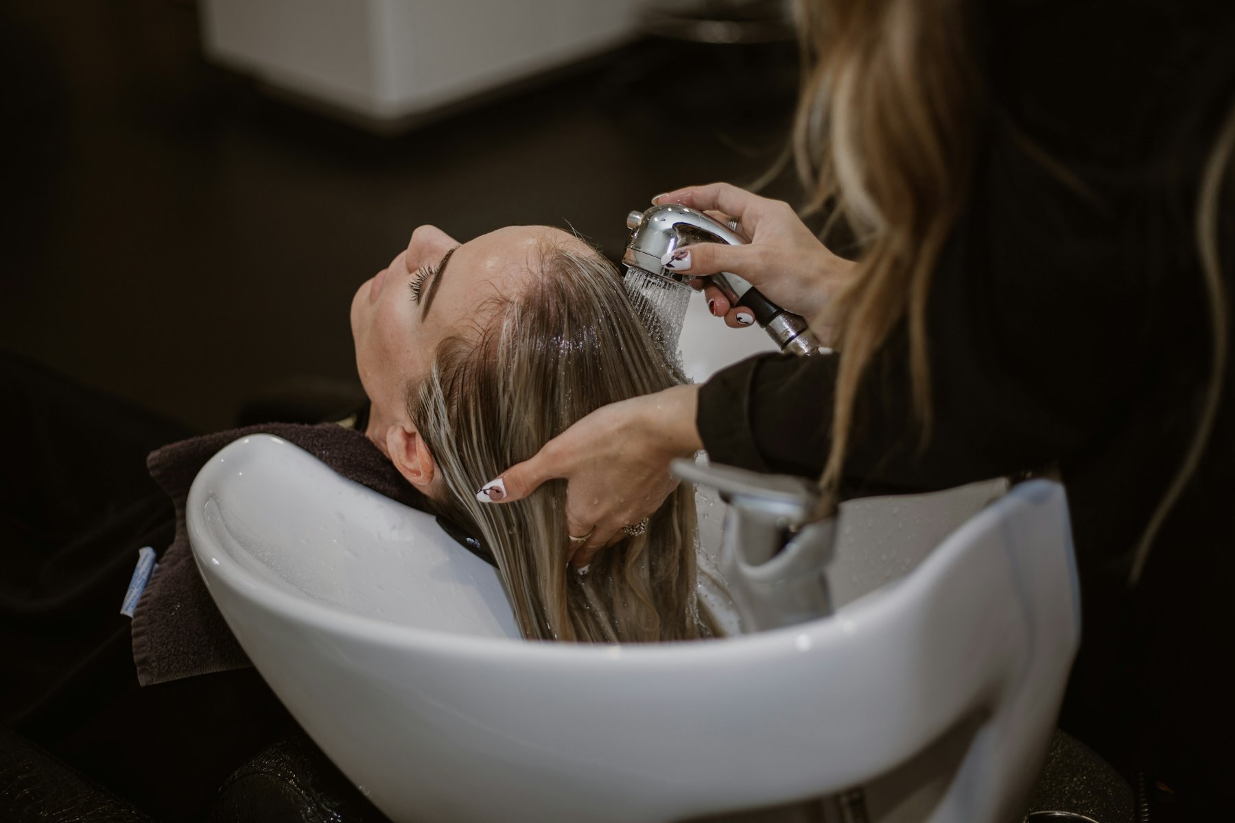 A stylist washing a client's hair at a salon basin
