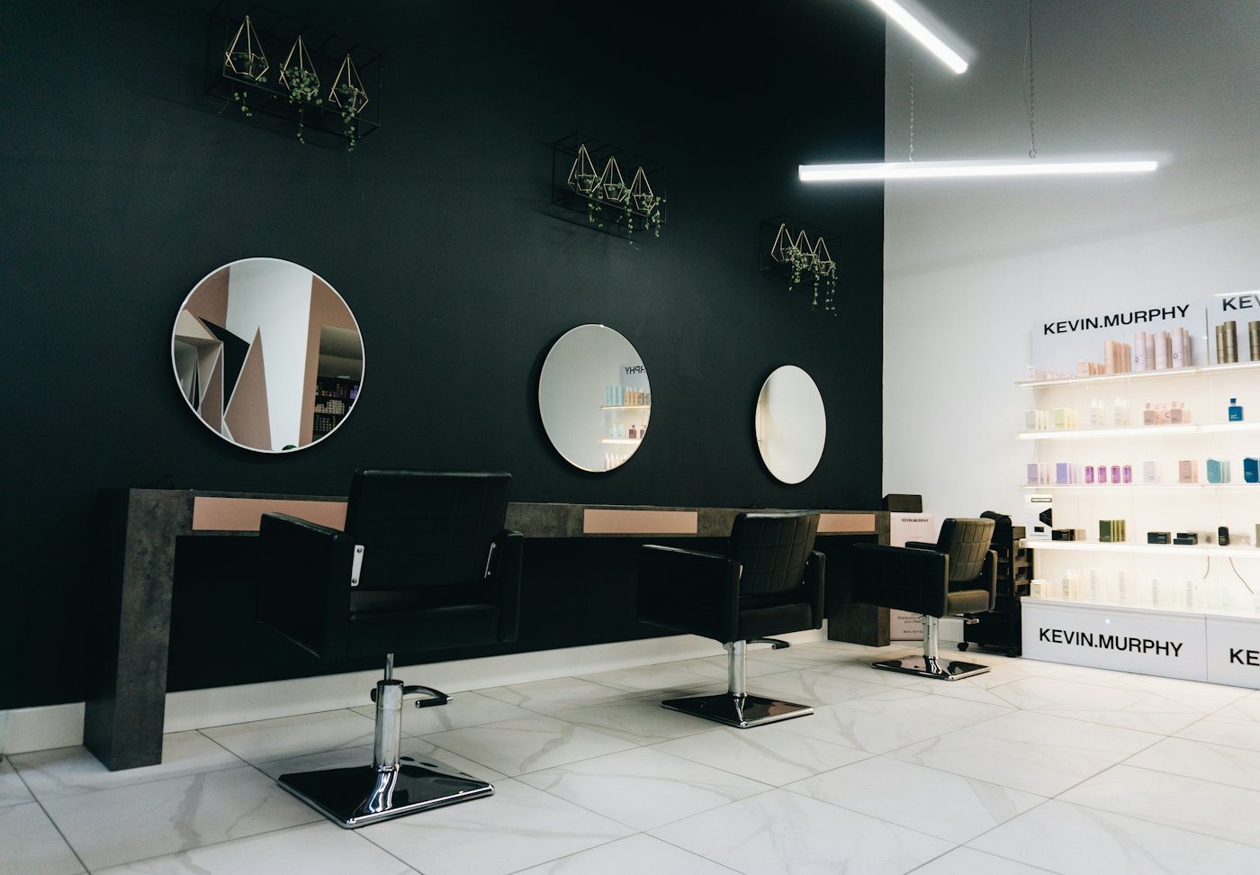 Salon styling stations with round mirrors against a dark wall