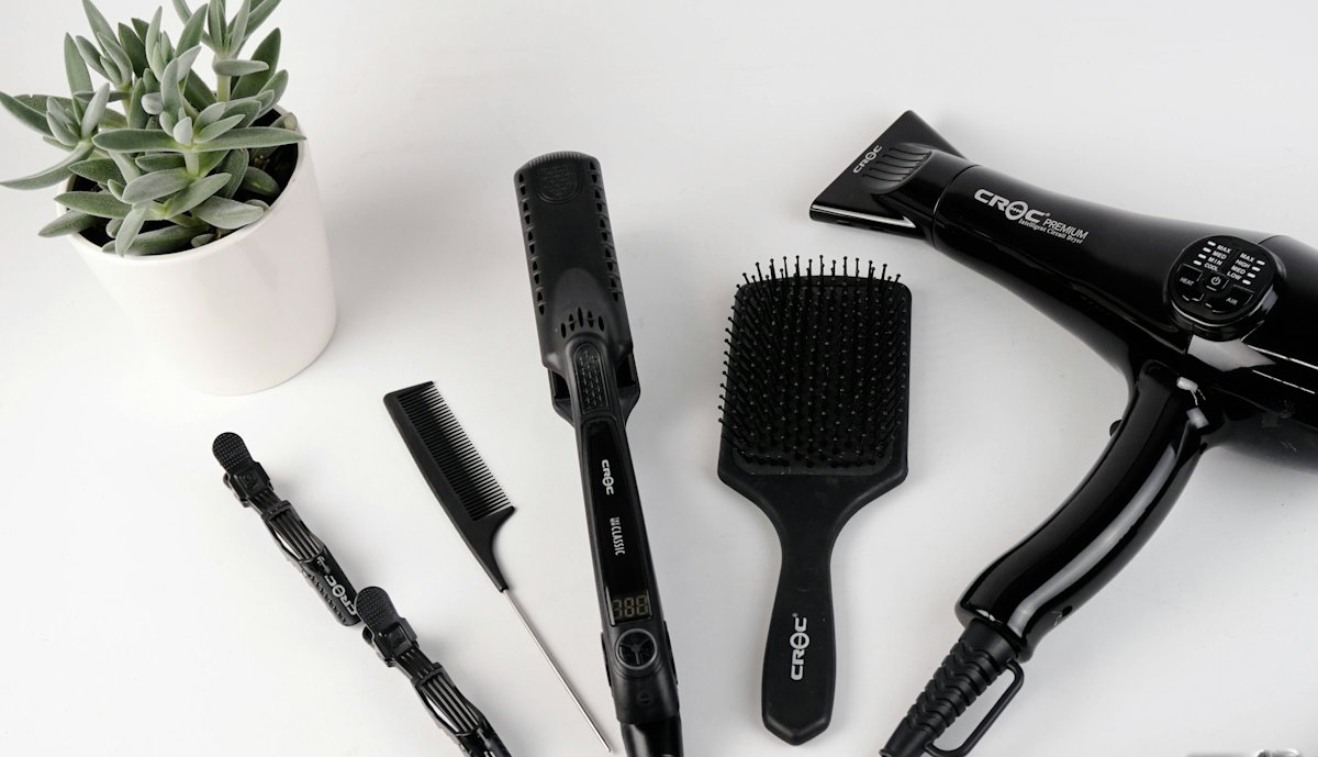 Hairdryer, brushes and combs laid out on a white surface